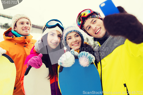 Image of happy friends with snowboards and smartphone