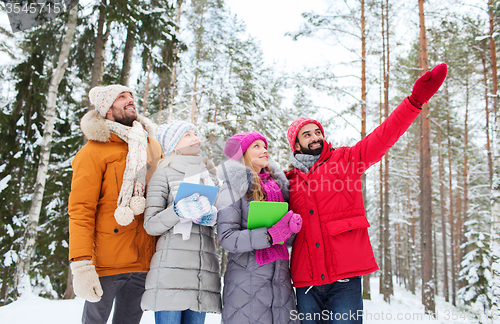 Image of smiling friends with tablet pc in winter forest