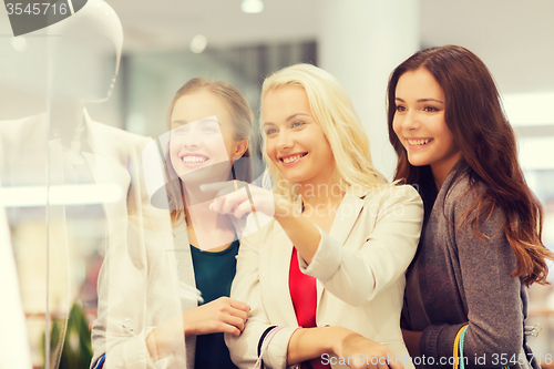 Image of happy young women with shopping bags in mall