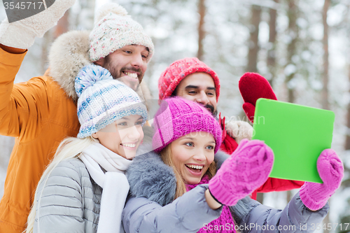 Image of smiling friends with tablet pc in winter forest