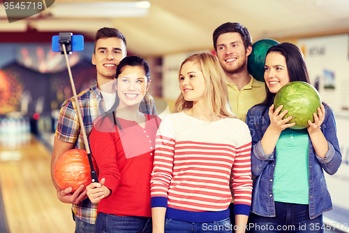 Image of happy friends taking selfie in bowling club