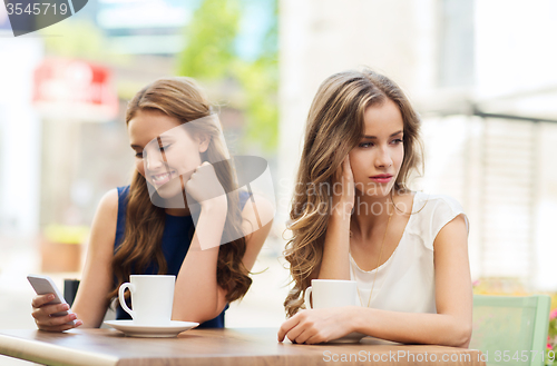 Image of women with smartphones and coffee at outdoor cafe