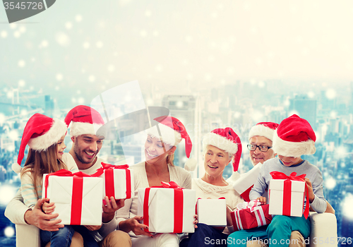 Image of happy family in santa helper hats with gift boxes