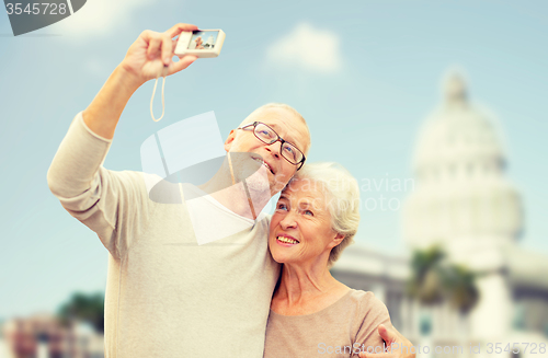 Image of senior couple with camera over white house