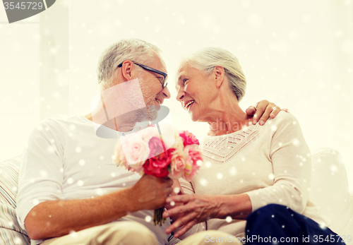 Image of happy senior couple with bunch of flowers at home