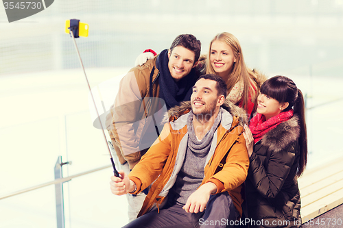 Image of happy friends with smartphone on skating rink