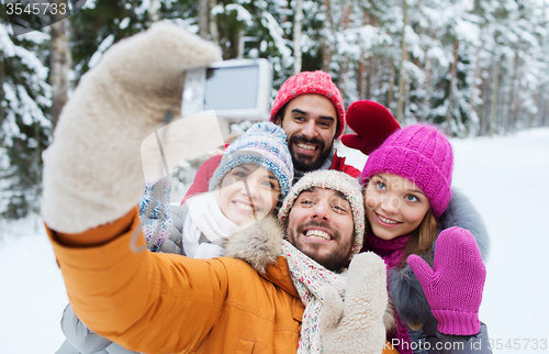 Image of smiling friends with camera in winter forest