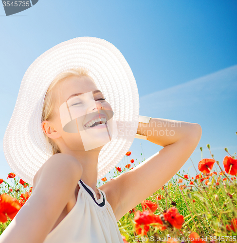 Image of smiling young woman in straw hat on poppy field