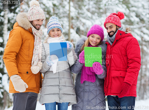 Image of smiling friends with tablet pc in winter forest