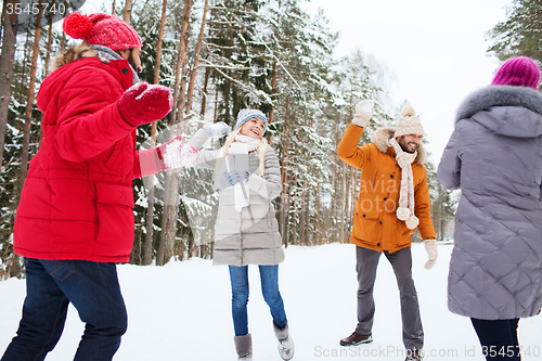 Image of happy friends playing snowball in winter forest