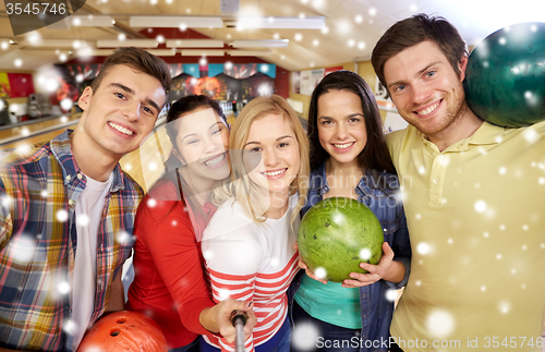 Image of happy friends taking selfie in bowling club