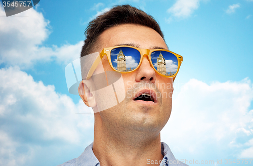 Image of face of man in sunglasses looking at big ben tower