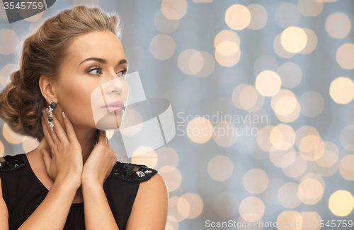 Image of beautiful woman wearing earrings over lights