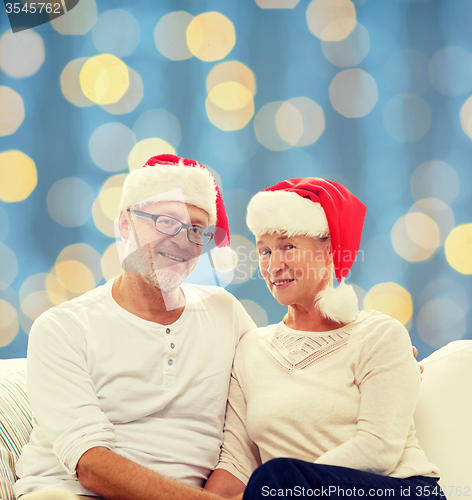 Image of happy senior couple in santa helper hats