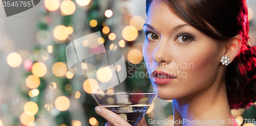 Image of woman with cocktail over christmas tree lights