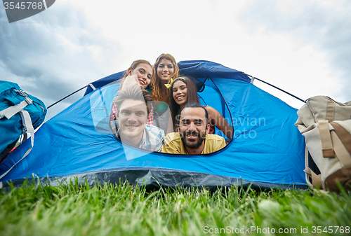 Image of happy friends with backpacks in tent at camping