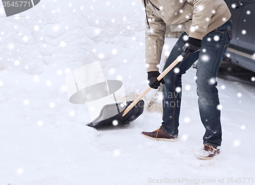 Image of closeup of man digging snow with shovel near car