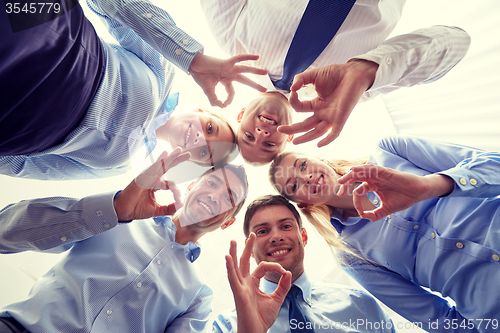 Image of smiling group of businesspeople standing in circle