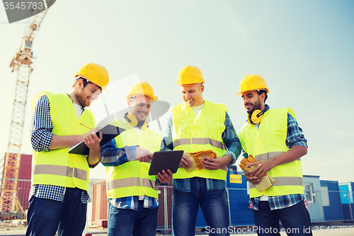 Image of group of smiling builders with tablet pc outdoors