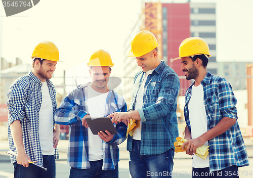 Image of group of smiling builders with tablet pc outdoors