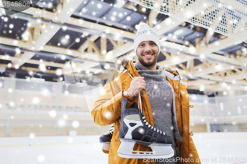 Image of happy young man with ice-skates on skating rink