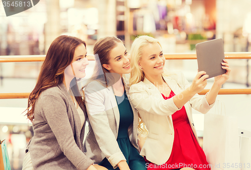 Image of happy young women with tablet pc and shopping bags