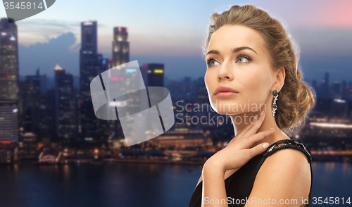 Image of beautiful woman wearing earrings over evening city