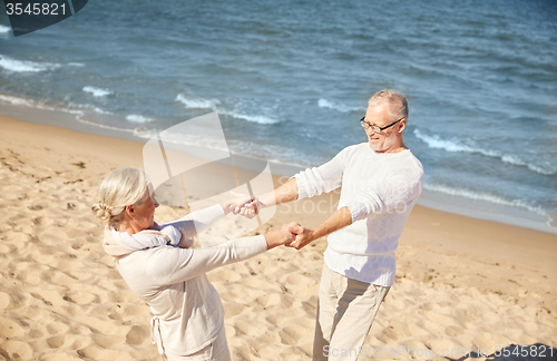 Image of happy senior couple holding hands on summer beach