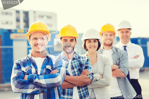 Image of group of smiling builders in hardhats outdoors