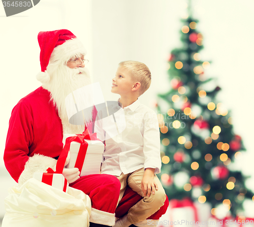 Image of smiling little boy with santa claus and gifts