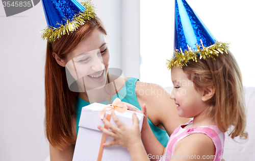 Image of happy mother and child in party caps with gift box