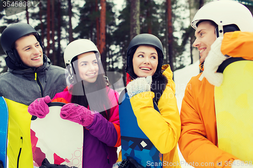 Image of happy friends in helmets with snowboards talking