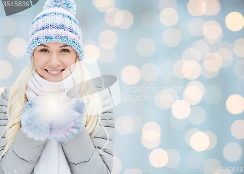 Image of smiling young woman in winter clothes over lights