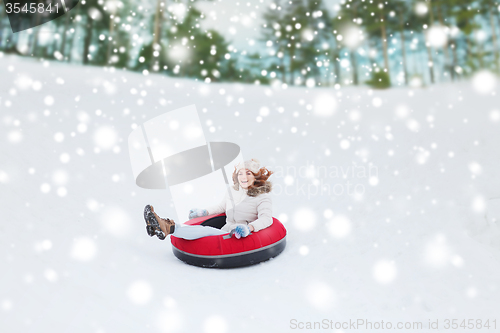 Image of happy teenage girl sliding down on snow tube