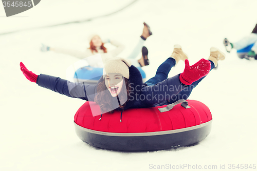 Image of group of happy friends sliding down on snow tubes