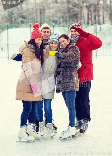 Image of happy friends with smartphone on ice skating rink