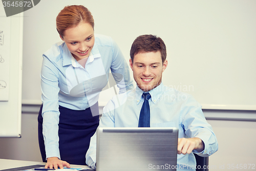 Image of smiling businesspeople with laptop in office