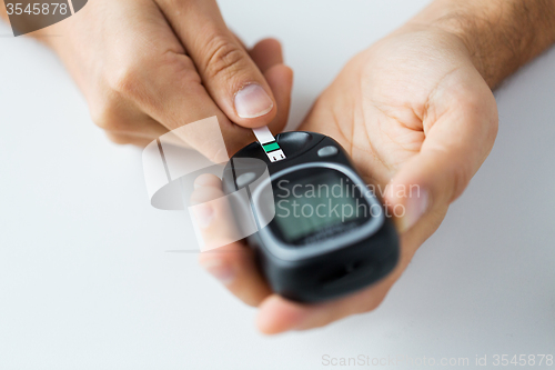 Image of close up of man checking blood sugar by glucometer