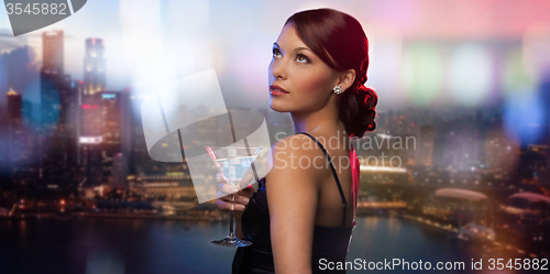 Image of smiling woman holding cocktail over night city