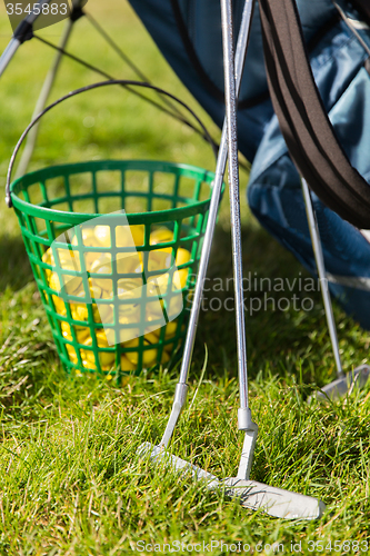 Image of close up of golf club and balls in basket on grass