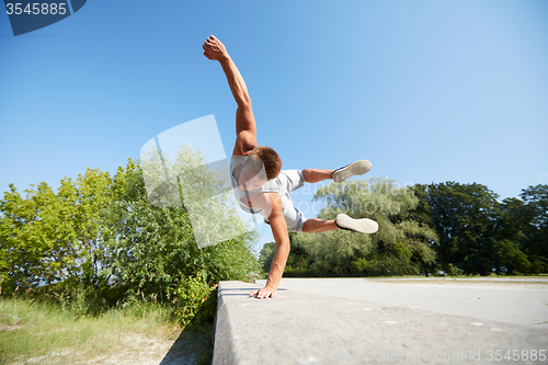 Image of sporty young man jumping in summer park