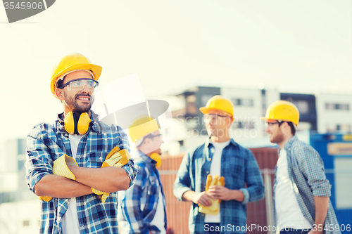 Image of group of smiling builders in hardhats outdoors