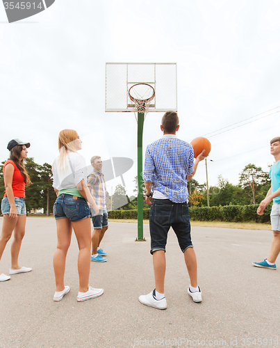 Image of group of happy teenagers playing basketball