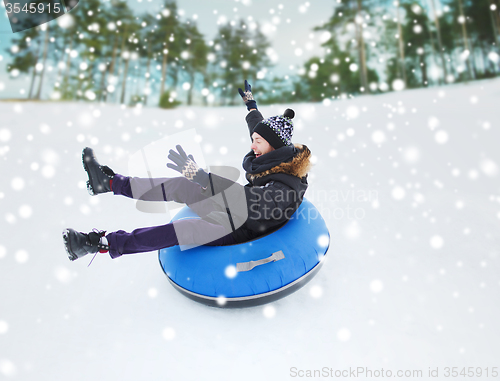 Image of happy young man sliding down on snow tube