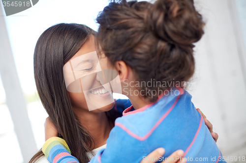 Image of happy mother and daughter hugging at home