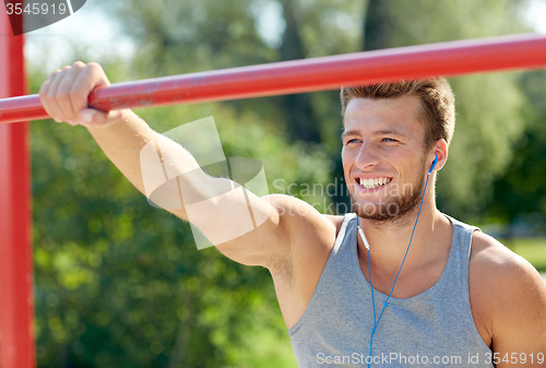 Image of happy young man with earphones and horizontal bar