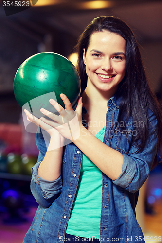 Image of happy young woman holding ball in bowling club