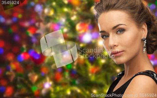 Image of beautiful woman wearing earrings over lights