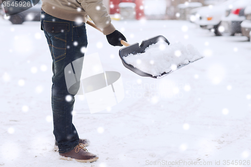 Image of closeup of man digging snow with shovel near car