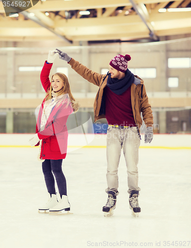 Image of happy couple holding hands on skating rink